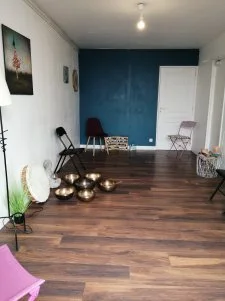La salle de pratique du cabinet : parquet, mur bleu canard, bols tibétains et chaises